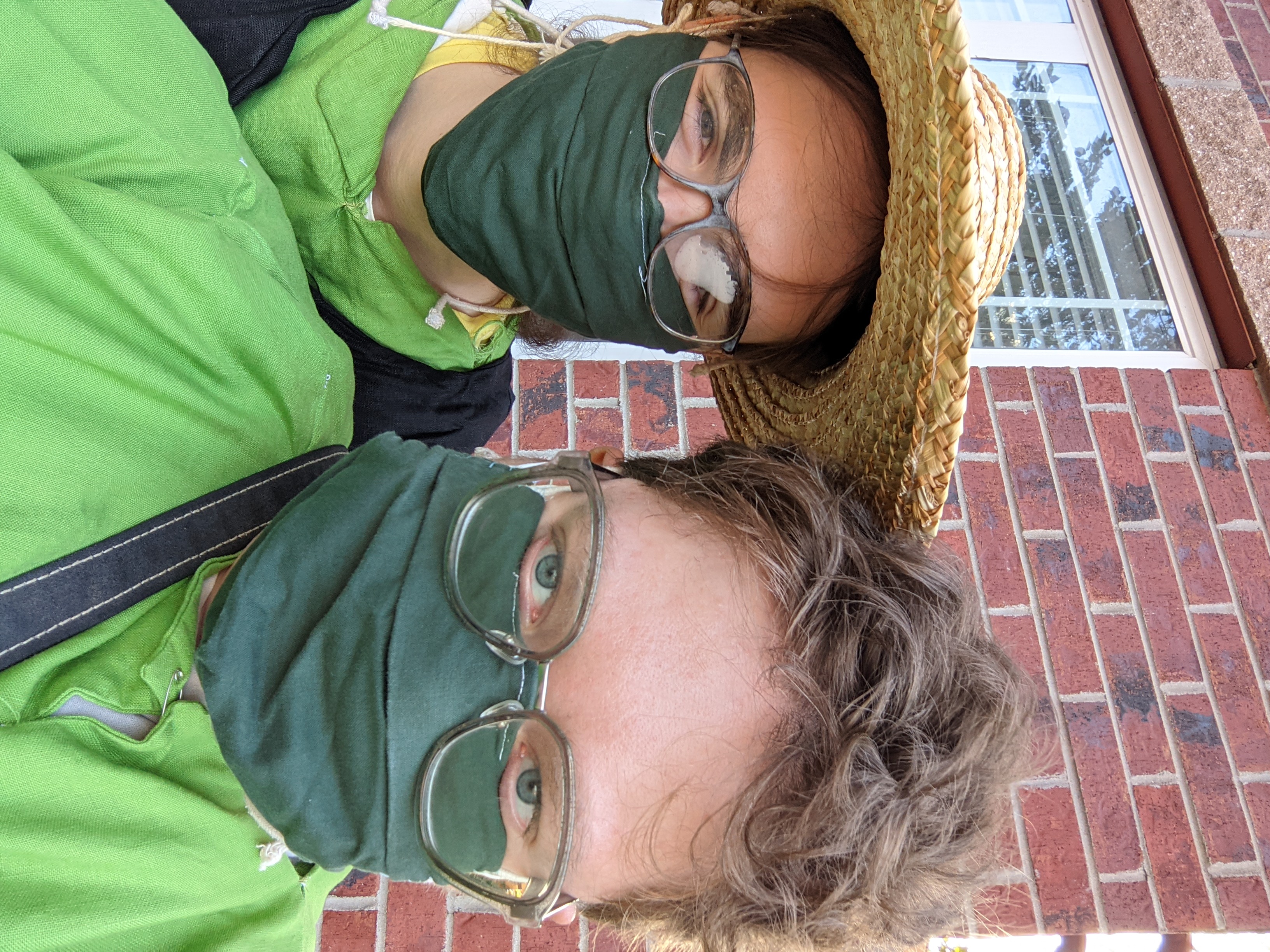 Selfie of two smiling people in masks and green cotes.