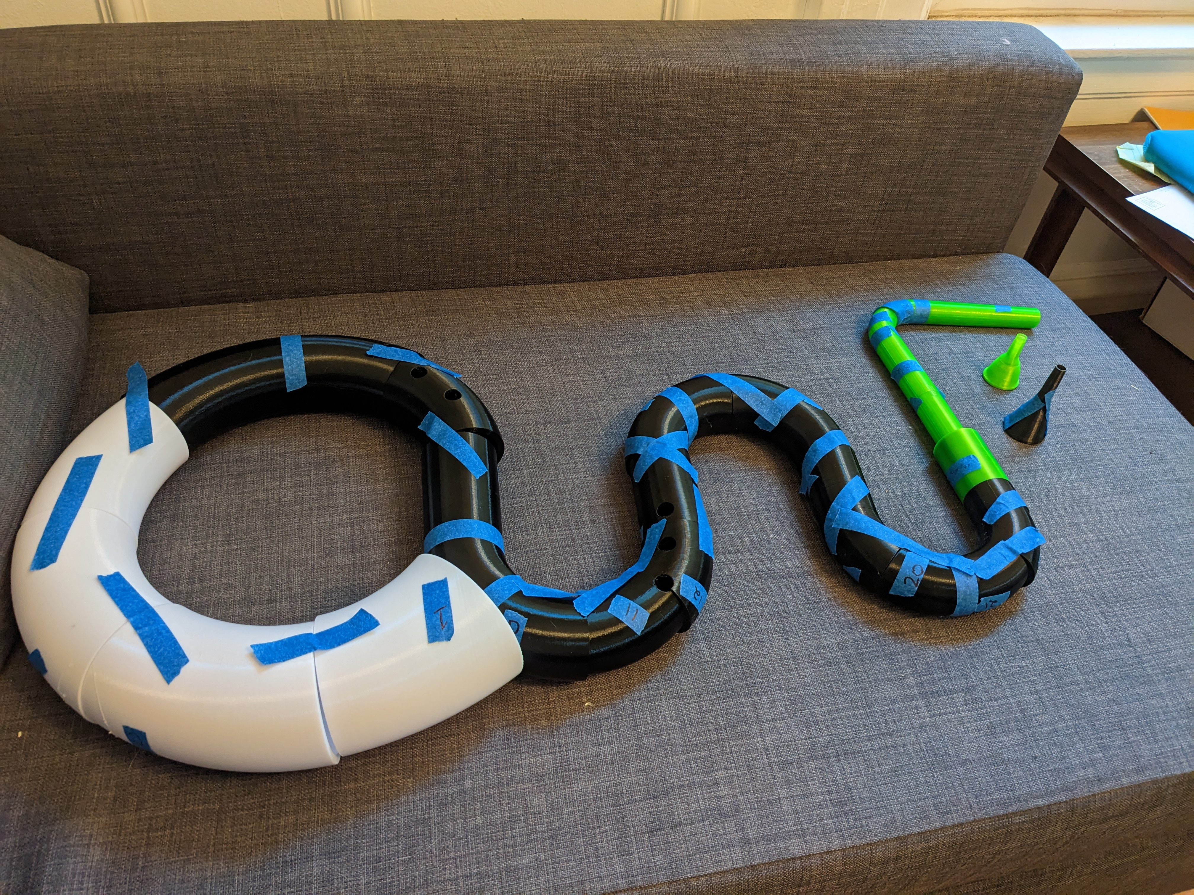 Serpent pieces taped together with blue tape on gray couch