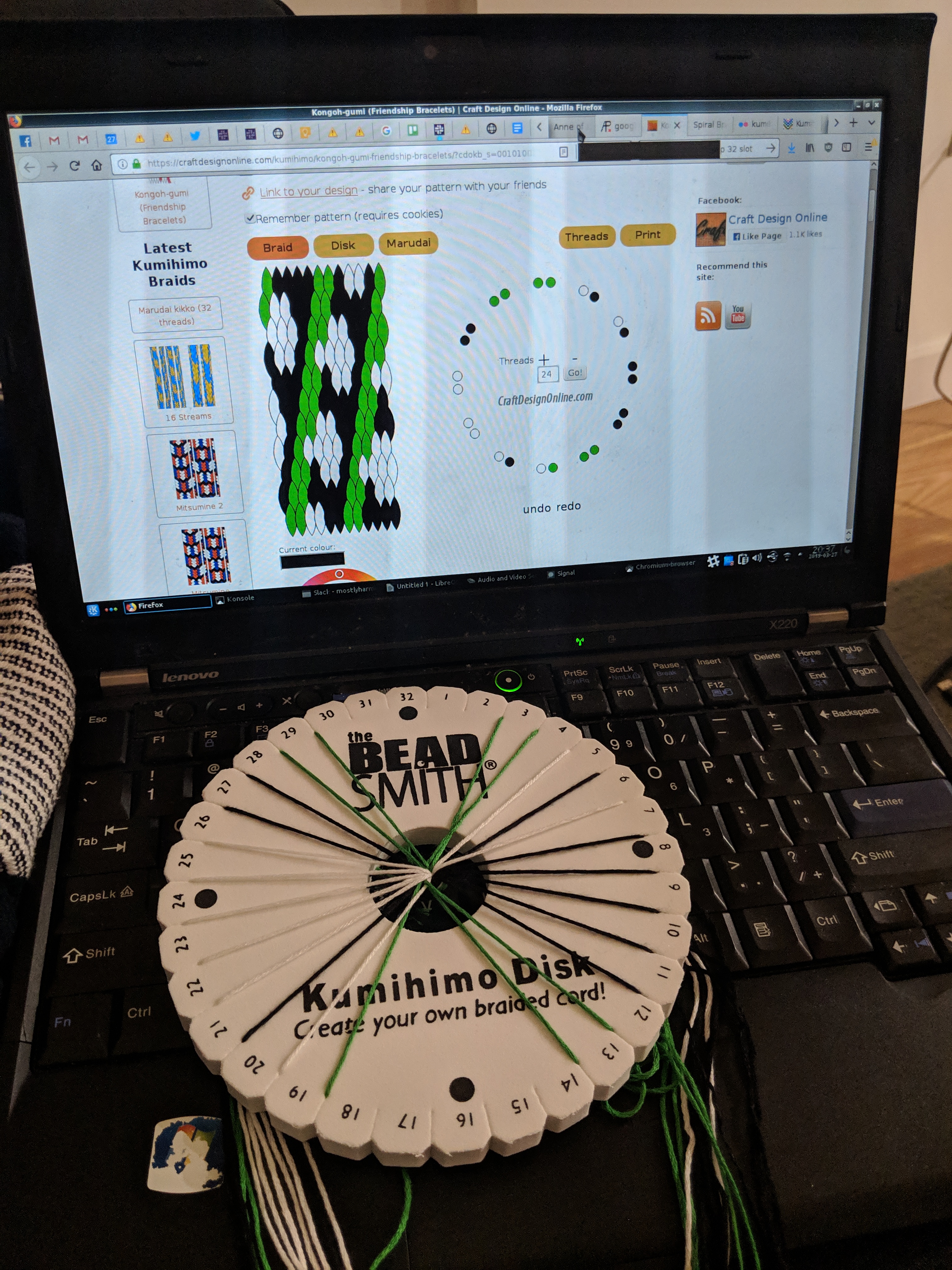 Picture of a threaded kumihimo disk in front of a computer screen with a kumihimo pattern on it 