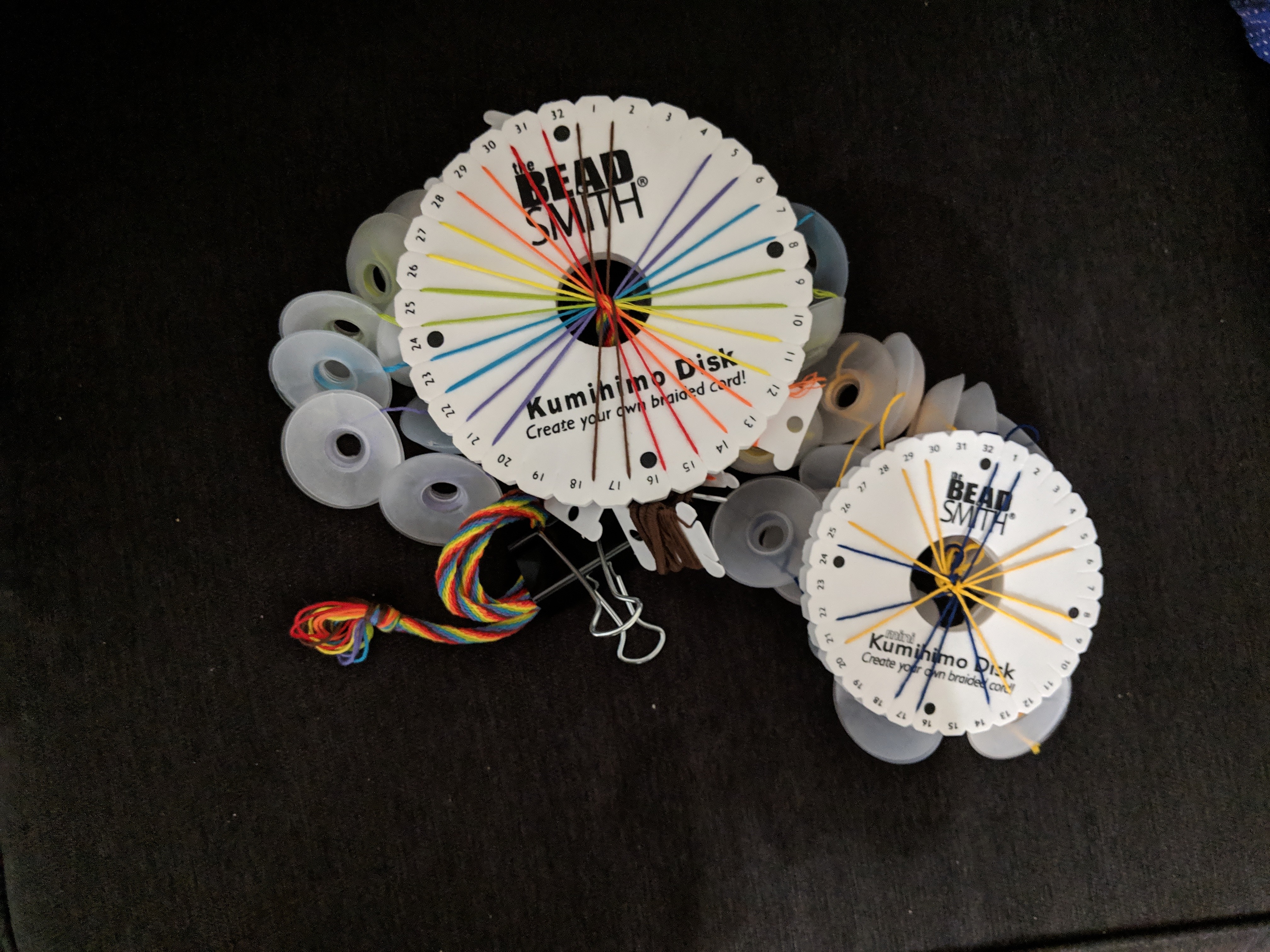 Picture of two kumihimo disks, one with rainbow braid, one with blue and yellow pattern.